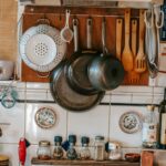 Collection of pans and culinary utensils near shelves with condiment bottles over gas stove at home