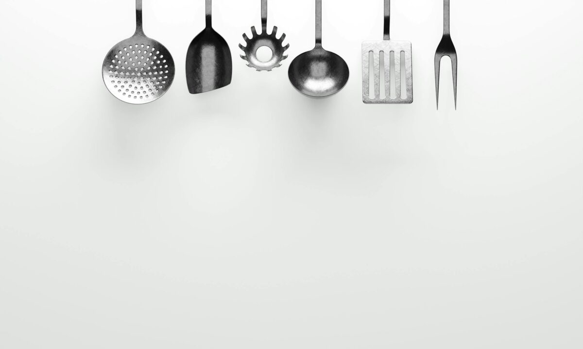 Hanging kitchen utensils against a clean white background.