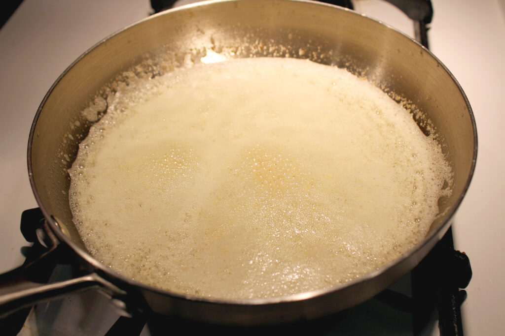 Butter browning in a pan on the stovetop. It is in the last stage of browning where it foams.