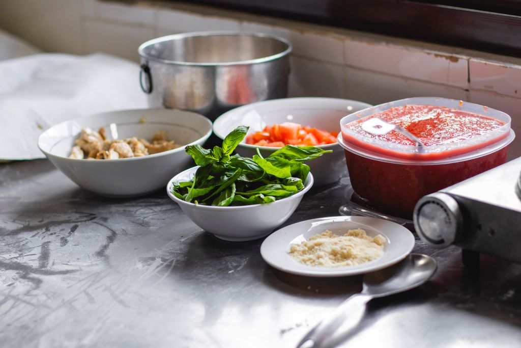 Mise en place: An arrangement of fresh ingredients including basil, tomatoes, and cheese on a kitchen counter for a delicious meal.