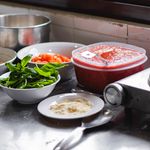 Mise en place: An arrangement of fresh ingredients including basil, tomatoes, and cheese on a kitchen counter for a delicious meal.