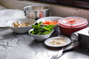 Mise en place: An arrangement of fresh ingredients including basil, tomatoes, and cheese on a kitchen counter for a delicious meal.
