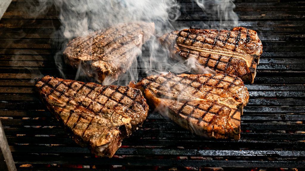 Perfectly grilled T-bone steaks sizzling on a BBQ grill using the two-zone grilling method