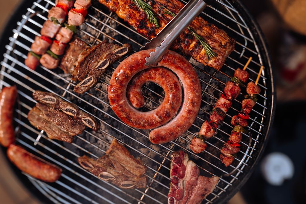 Sizzling variety of meats grilling on a barbecue, perfect for outdoor summer cookouts.